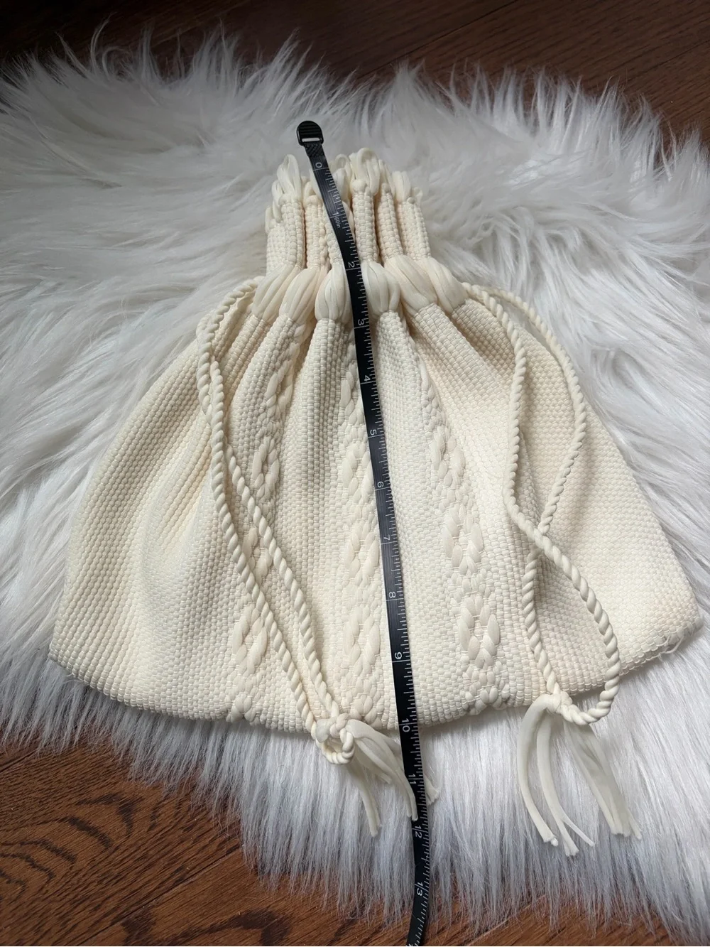Cream cable knit drawstring bag with braided rope details